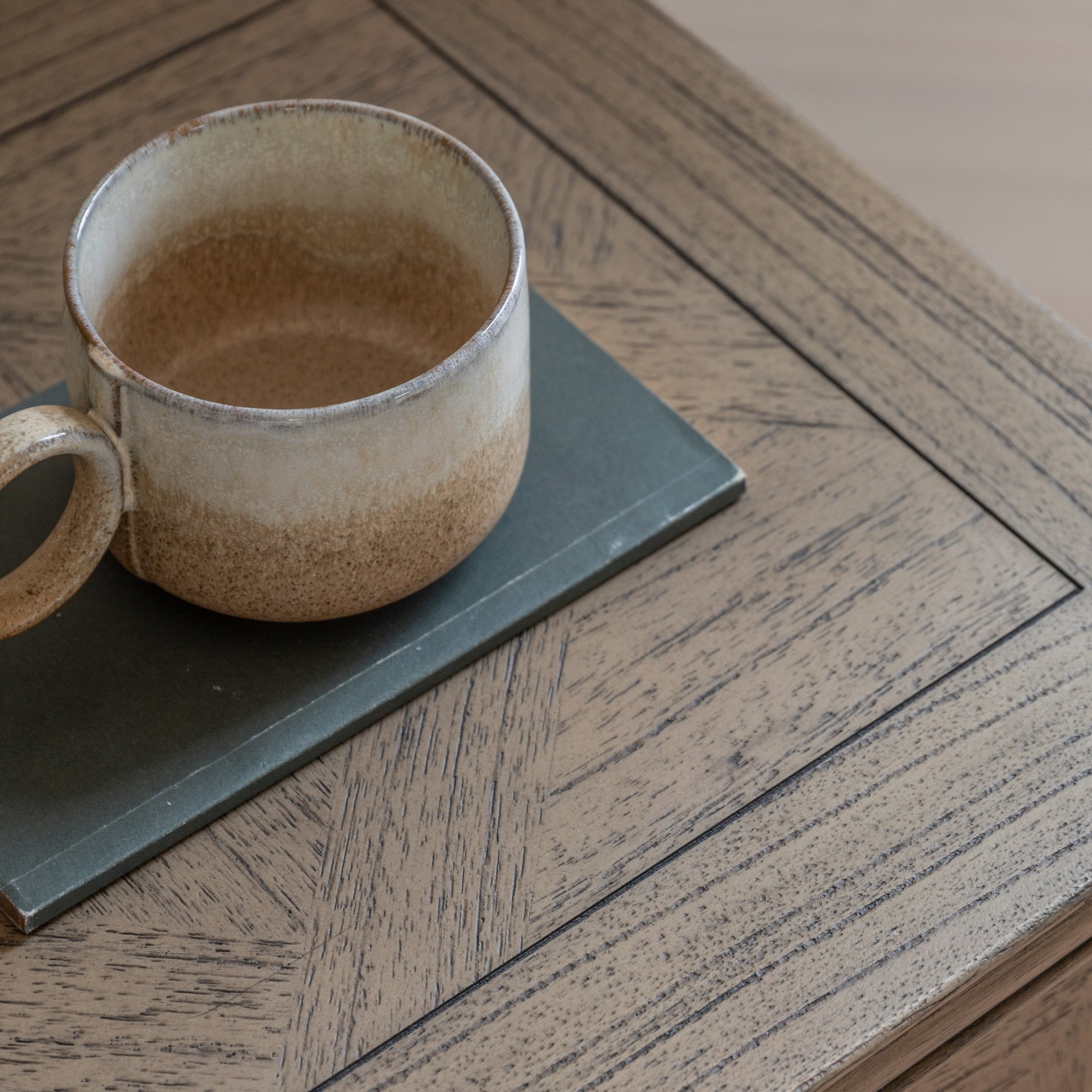 Close-up of a rustic wooden bedside table with a ceramic mug on top.
