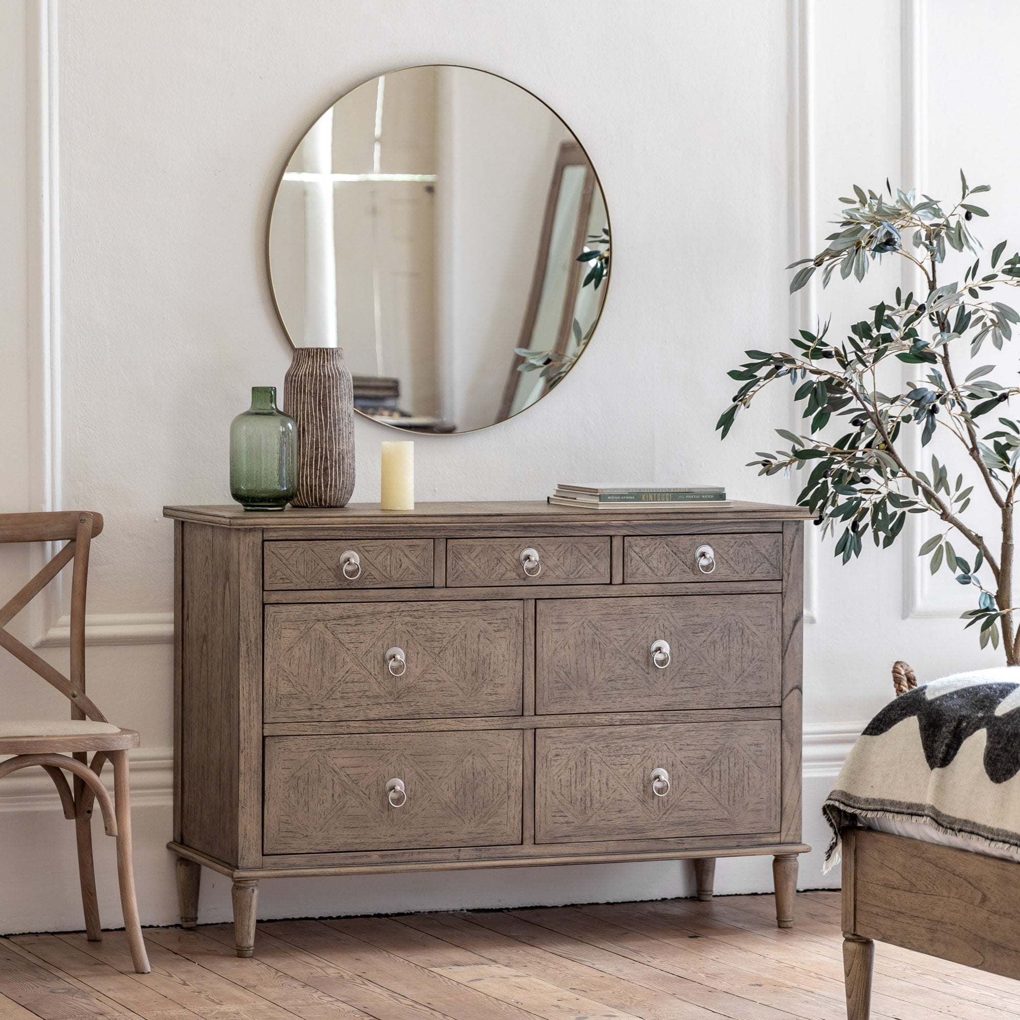 A seven-drawer dresser with a round mirror and decorative accents.