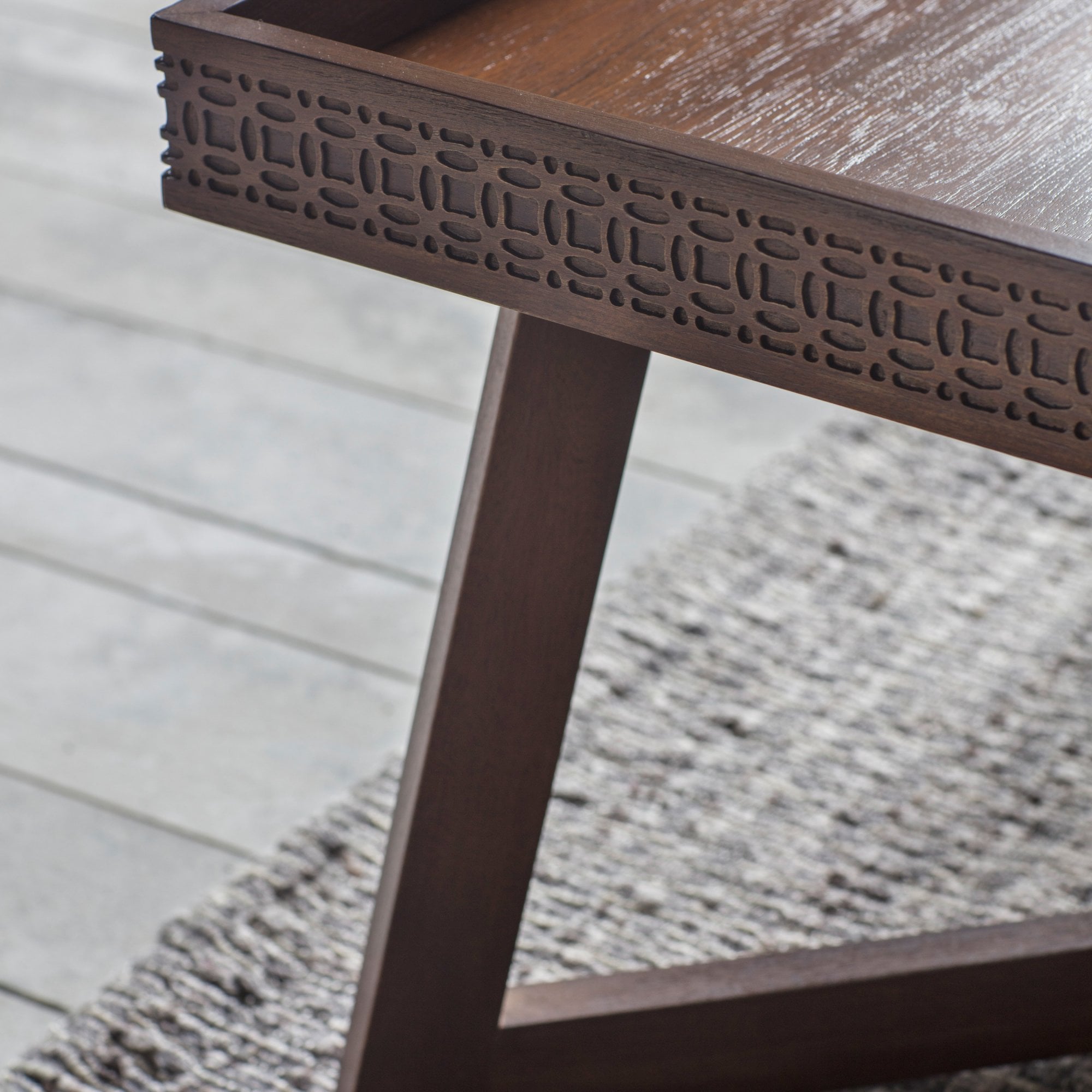 A close-up of the carved pattern on the wooden coffee table.