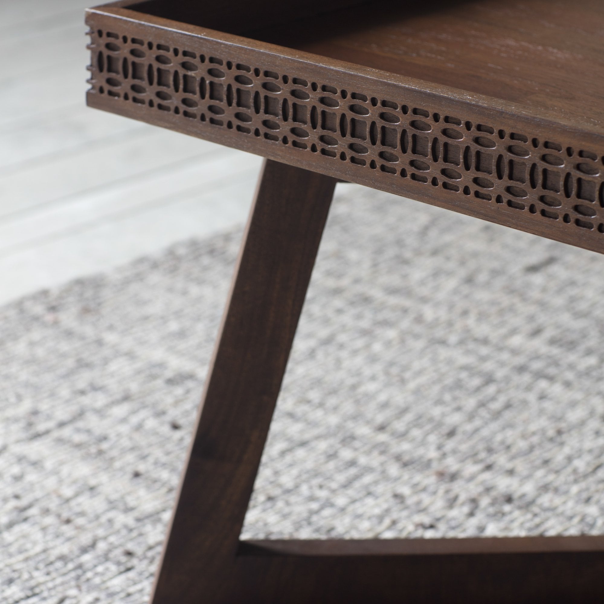 A detailed view of the carved pattern on the wooden coffee table.