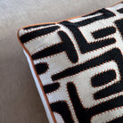 Close-up of a black and white patterned pillow with a distinct orange stitched edge.