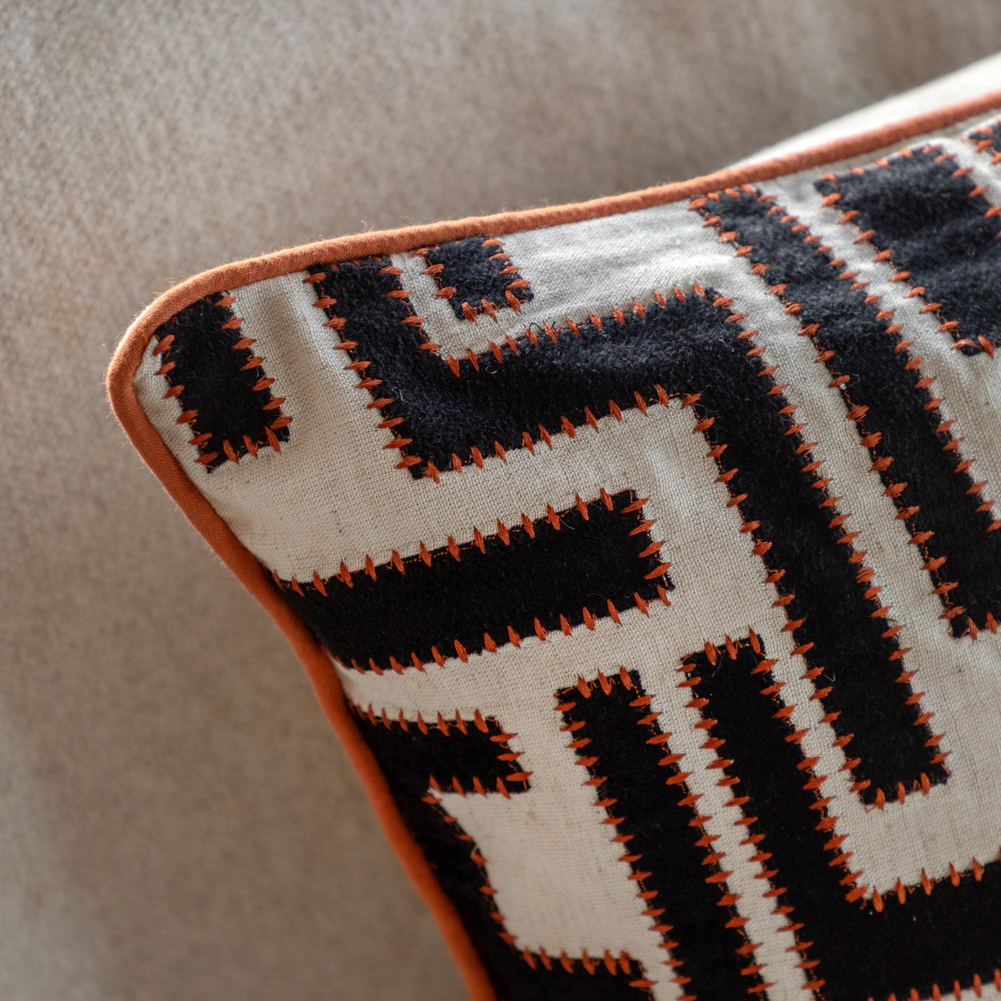 Close-up of the textured black and white pattern of a throw pillow with orange trim.