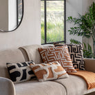 A living room scene with a sofa adorned with patterned throw pillows and a window view.