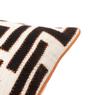 Close-up of a corner of the black and white geometric patterned pillow with orange trim.