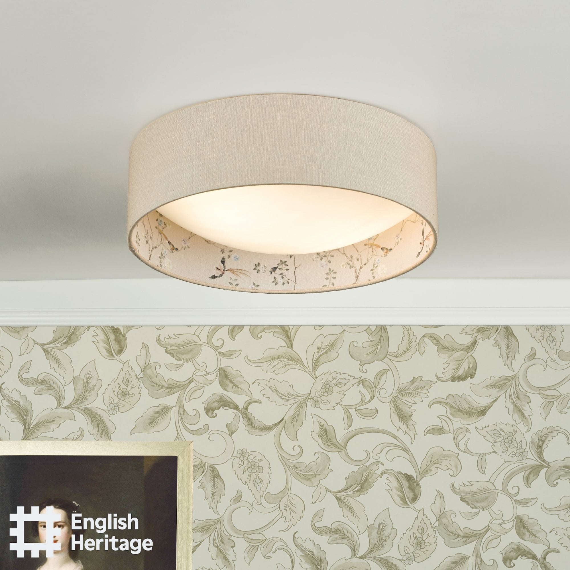 An English Heritage ceiling light with a bird and blossom pattern in a room with patterned wallpaper.