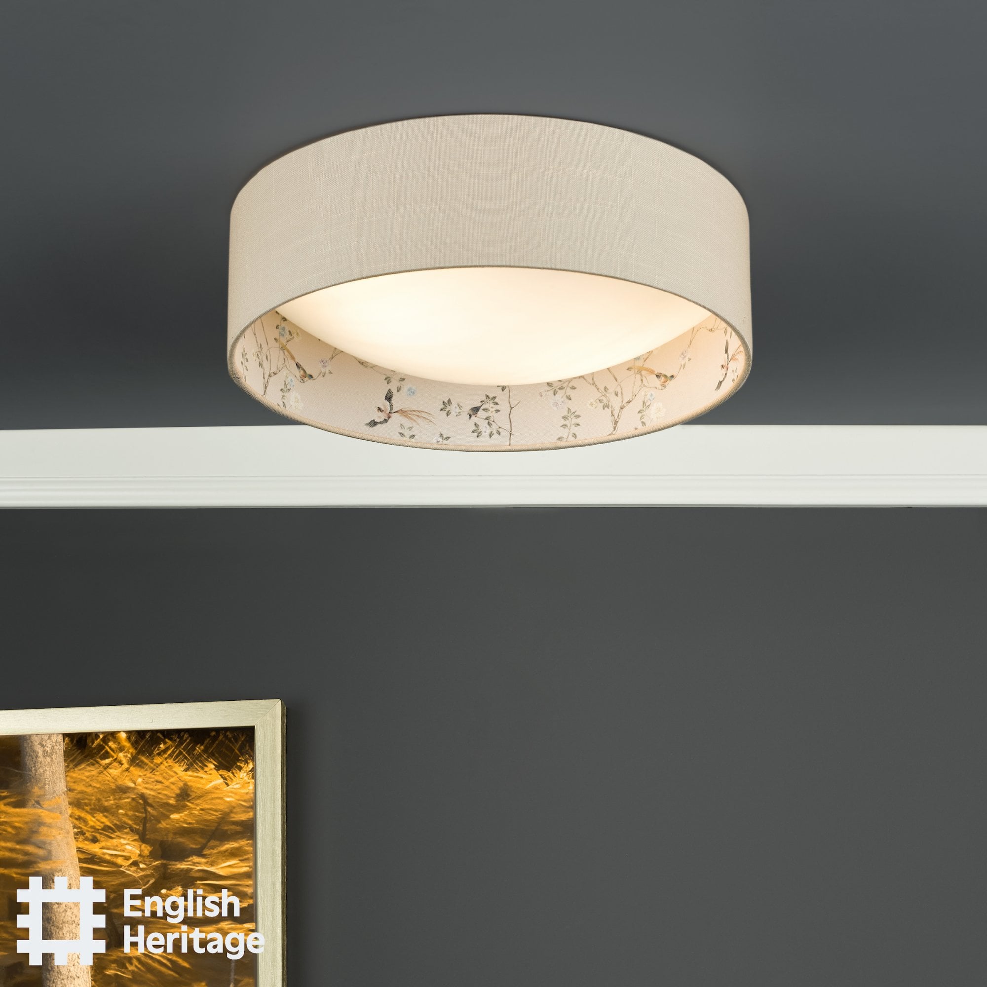 An English Heritage ceiling light with a bird and blossom pattern in a room with a grey wall.