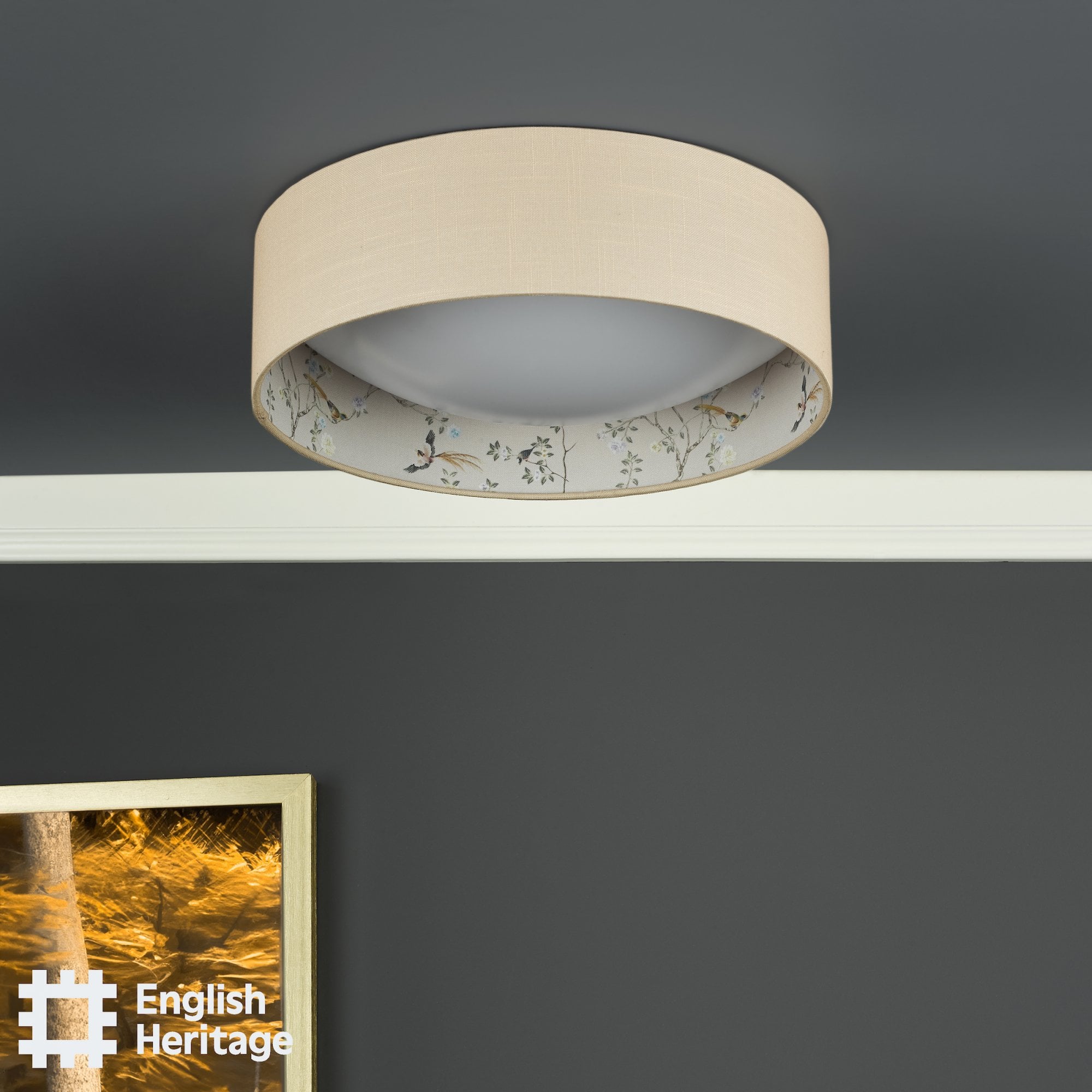 An English Heritage ceiling light with a bird and blossom pattern, off, in a room with a grey wall.
