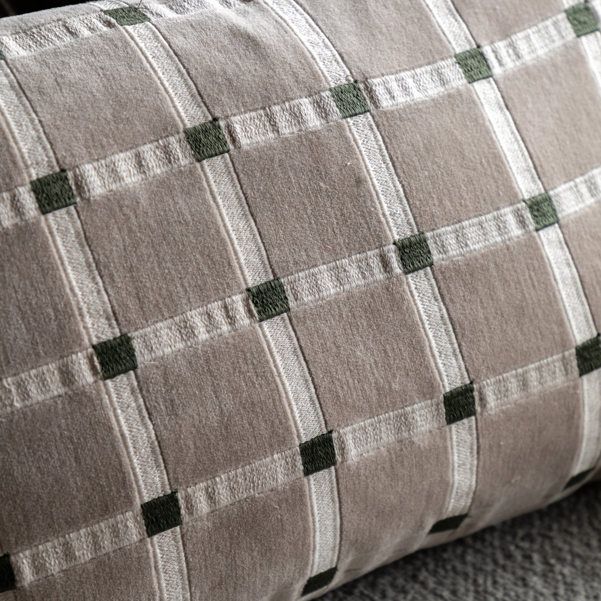 A close-up of the beige and white plaid pattern with green accents on the throw pillow.
