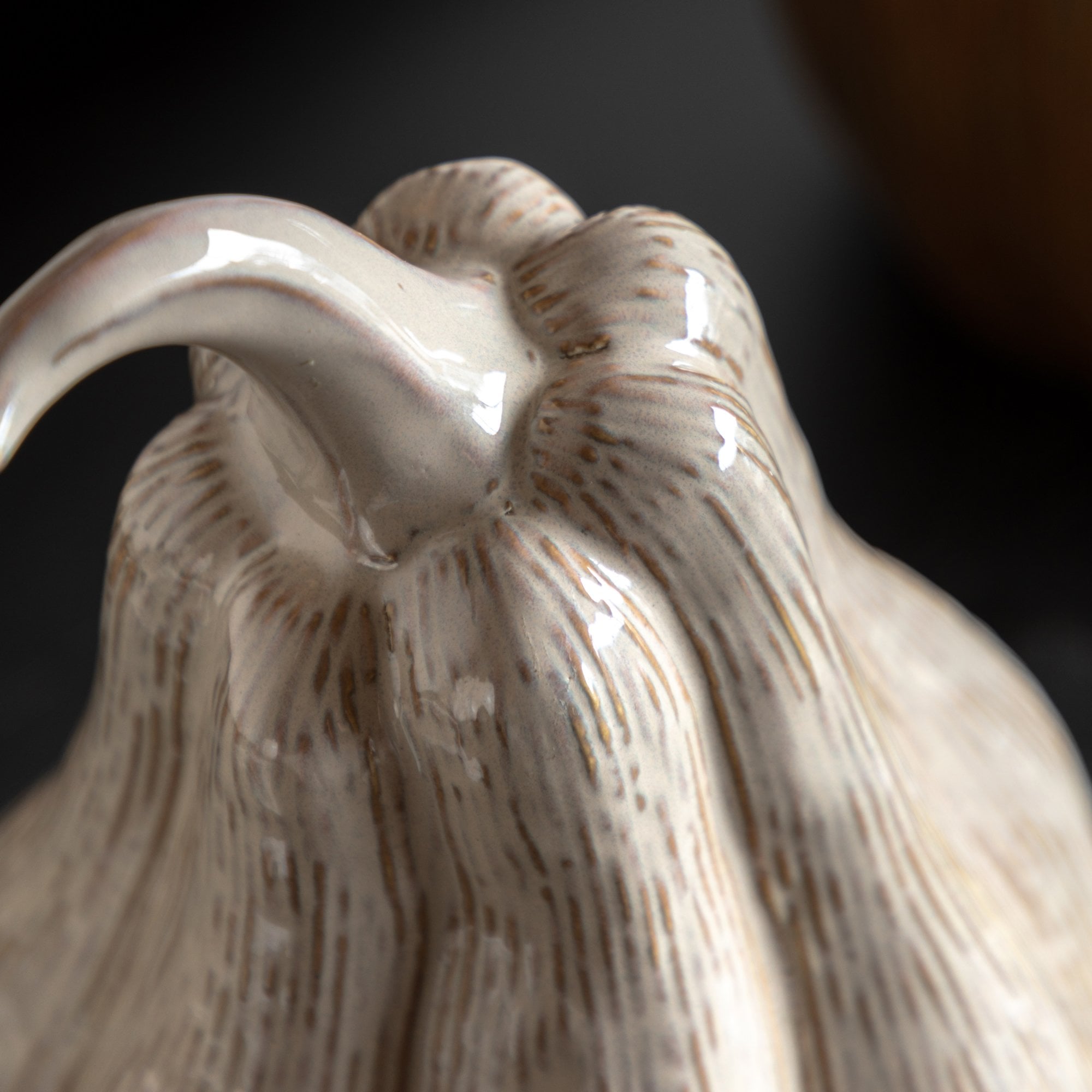 Close-up of the textured stem and top of a light beige ceramic gourd.
