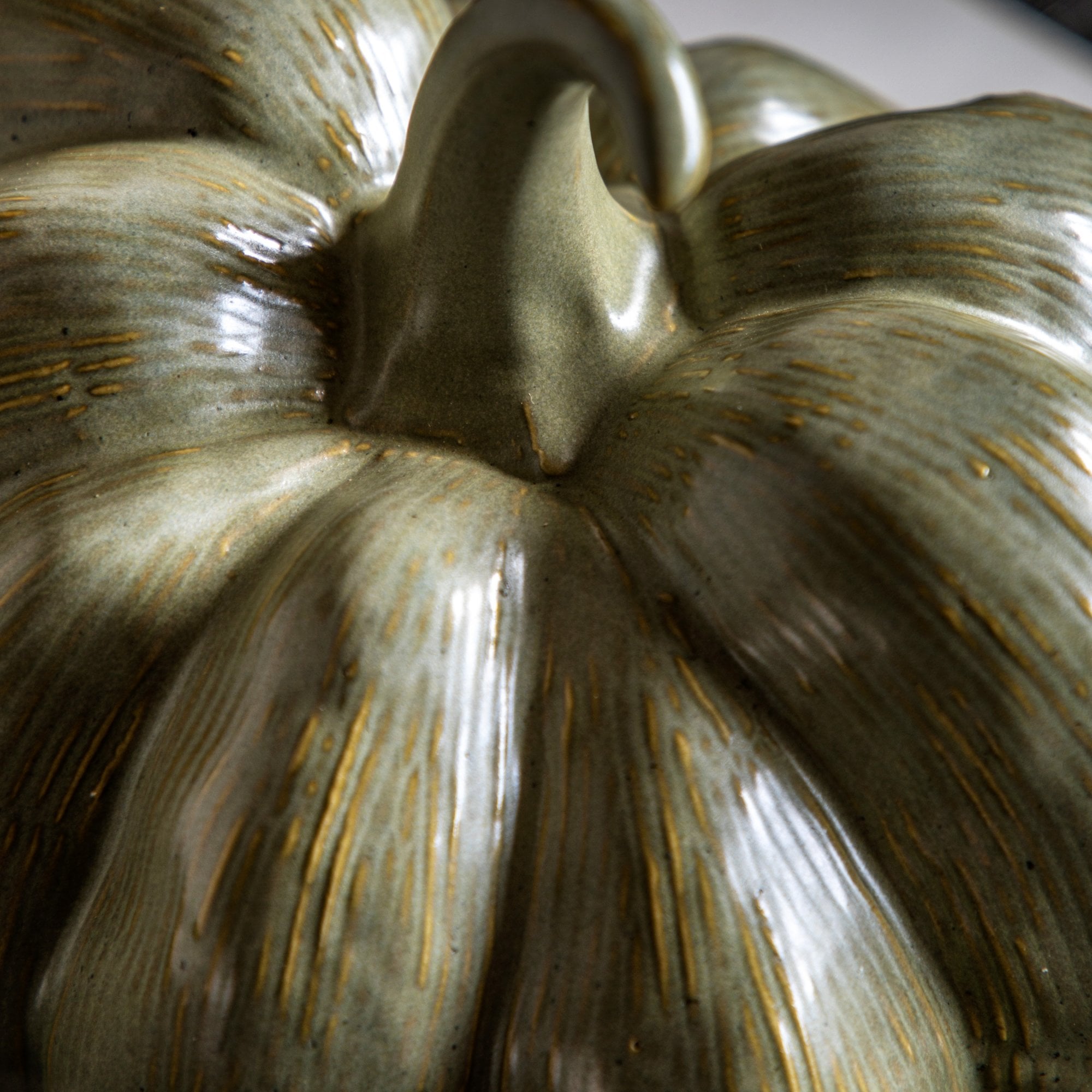Close-up of the textured surface of a green ceramic pumpkin.