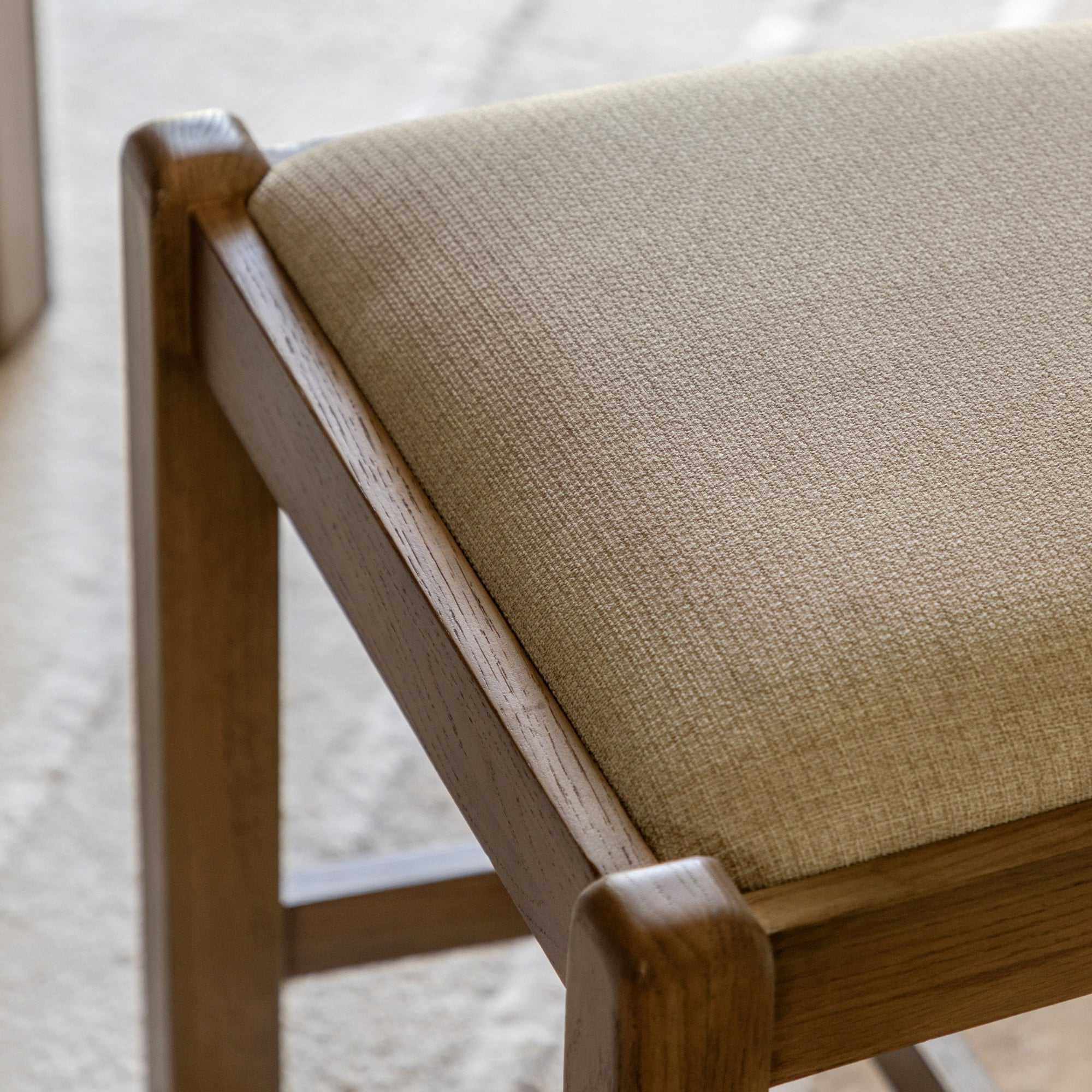 Close-up of the upholstered cream seat cushion on an oak dining chair.