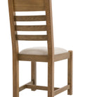 Back 3/4 view of a single oak ladder-back dining chair with a cream seat.
