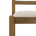 Close-up of the oak frame and cream upholstered seat of a dining chair.