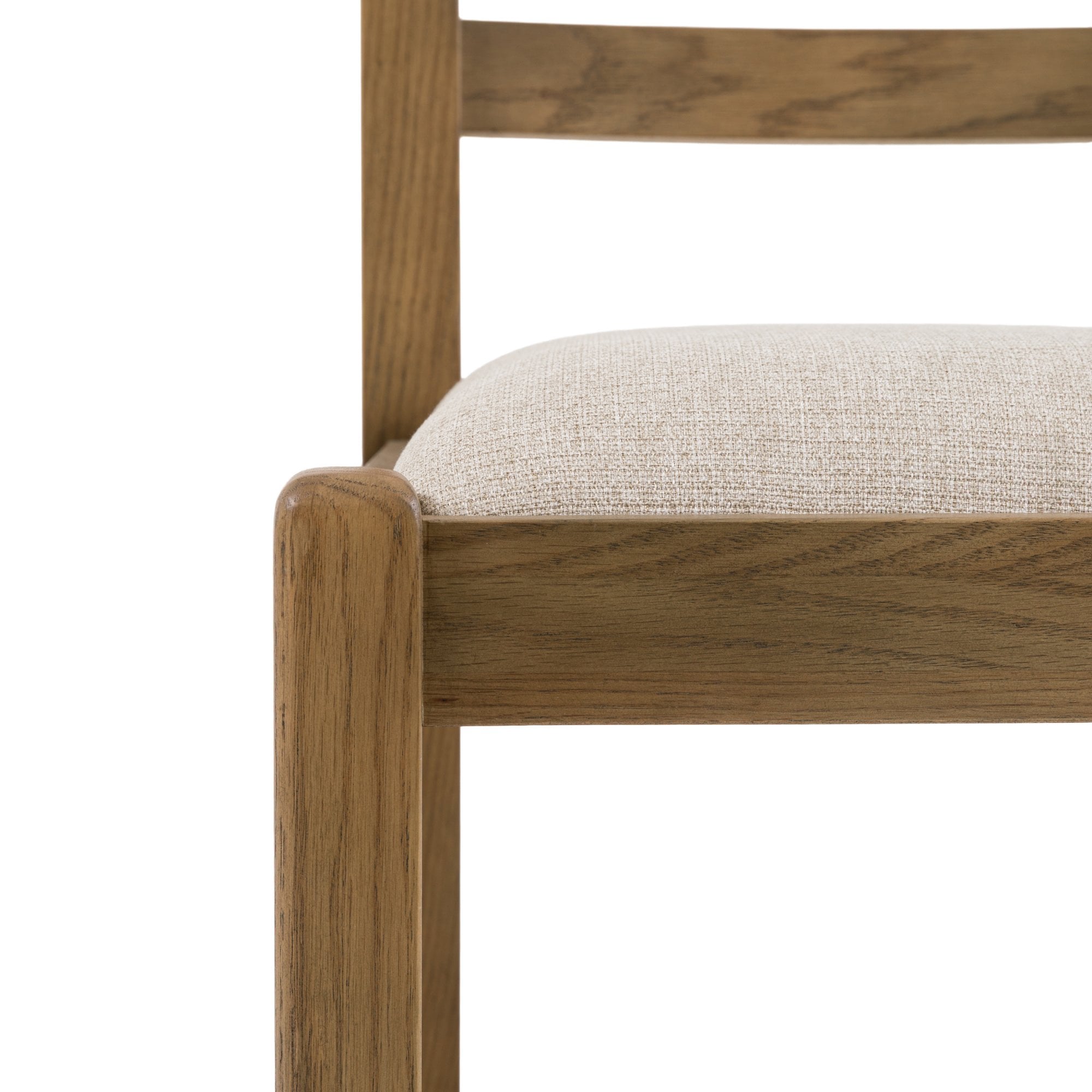 Close-up of the oak frame and cream upholstered seat of a dining chair.