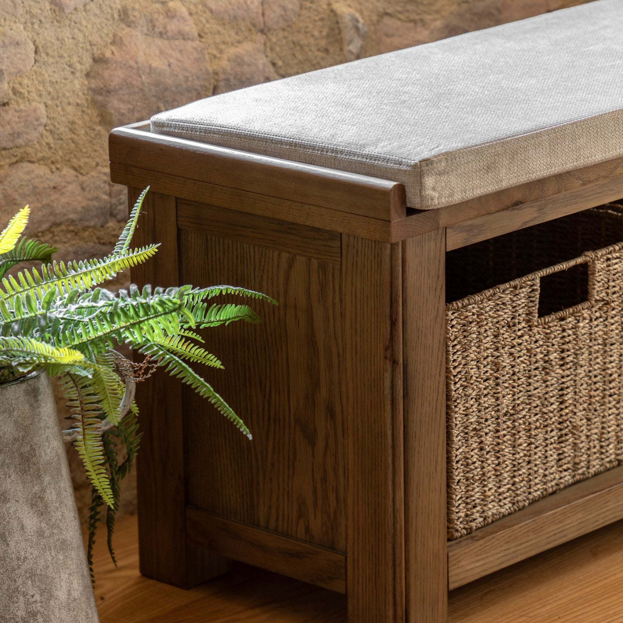 A close-up of the wooden storage bench with a wicker basket and a plant beside it.