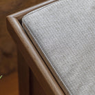 A close-up view of the corner of the cushioned top on the wooden storage bench.