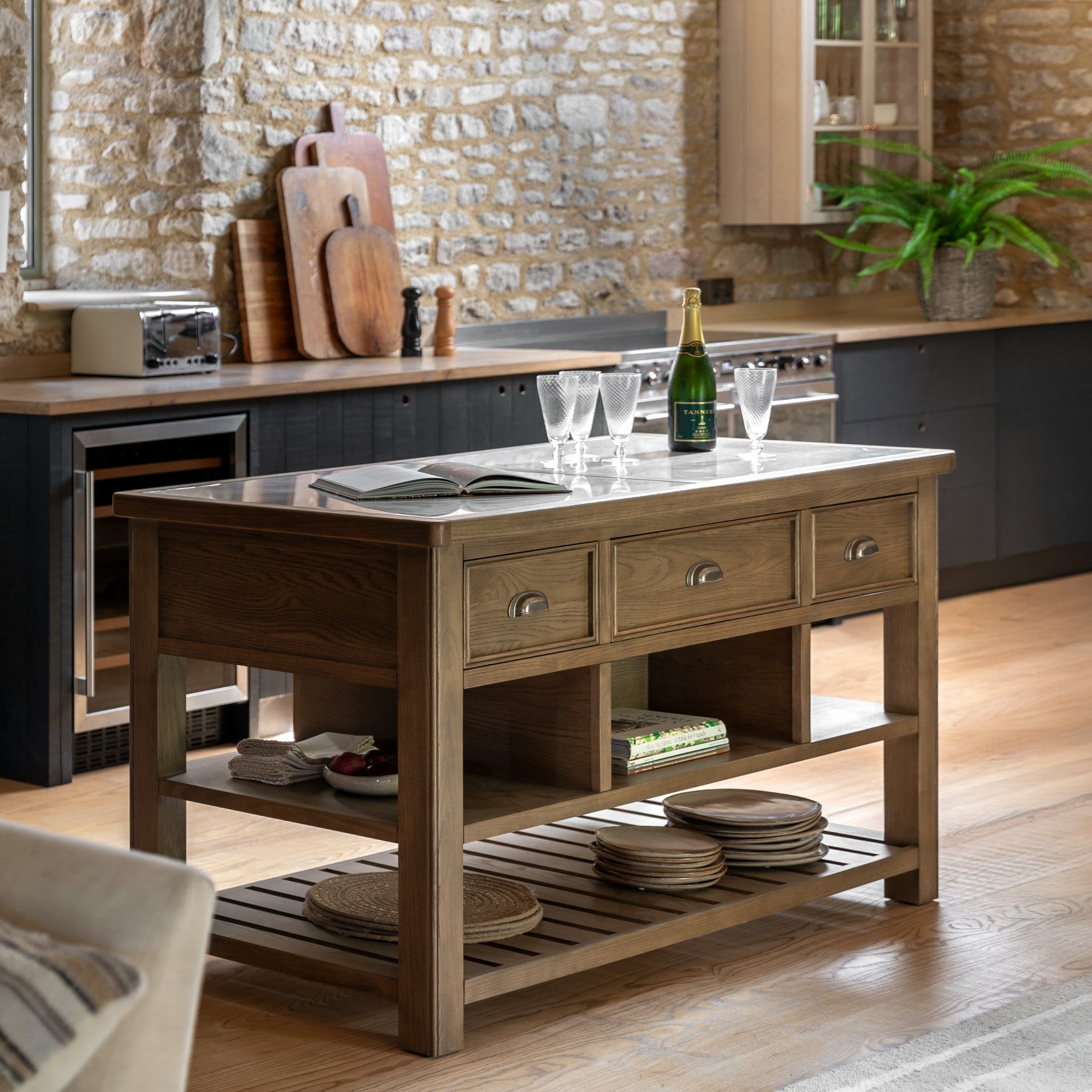 A rustic kitchen island with marble top, drawers, and open shelving, in a modern kitchen.