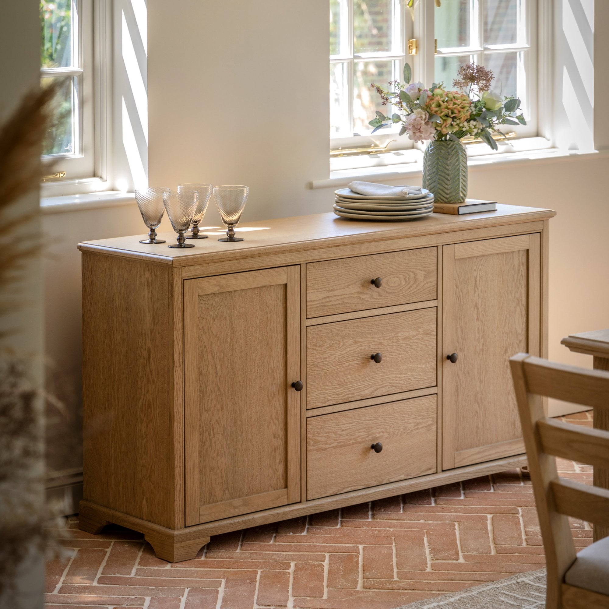 A large wooden sideboard in a kitchen with various items on top.