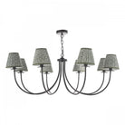 A black chandelier with eight arms and patterned lampshades.