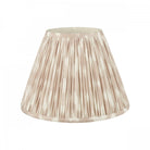 A pleated lamp shade in an off-white and pale brown vertical stripe pattern.