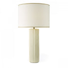 A white fluted table lamp with a cream shade, against a white background.