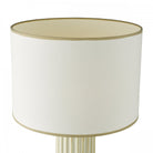 Close-up of the cream fabric shade with a gold trim from a table lamp.