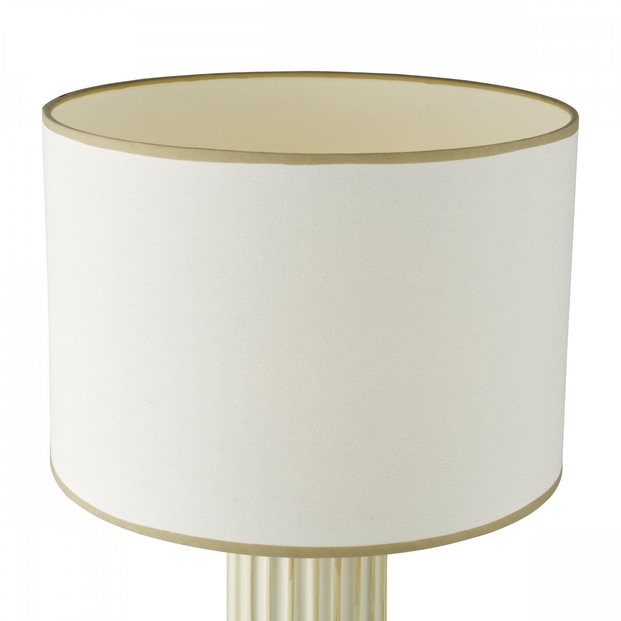 Close-up of the cream fabric shade with a gold trim from a table lamp.