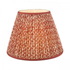 A pleated red and white patterned lamp shade with a solid red trim.
