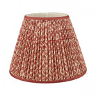 A pleated red and white patterned lamp shade with a solid red trim.