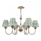 A brass chandelier with six green pleated shades.