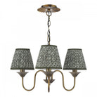 A vintage brass chandelier with three patterned green fabric shades.