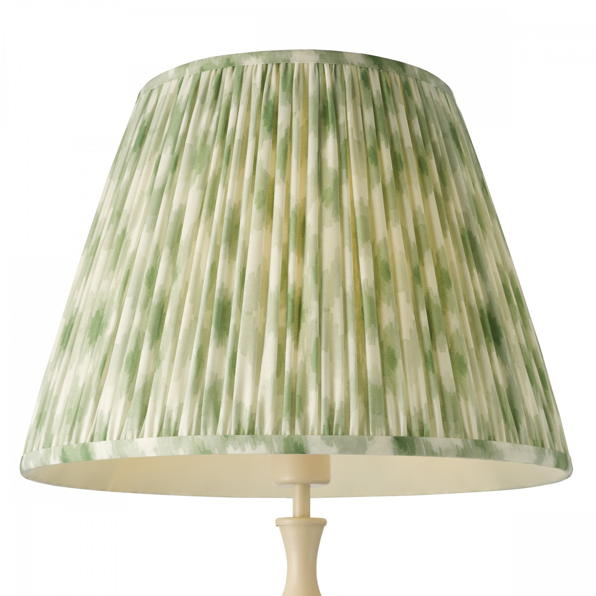 Green and white pleated lampshade on a lamp.