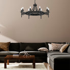 A black, round chandelier hanging above a dark grey sectional sofa in a living room.