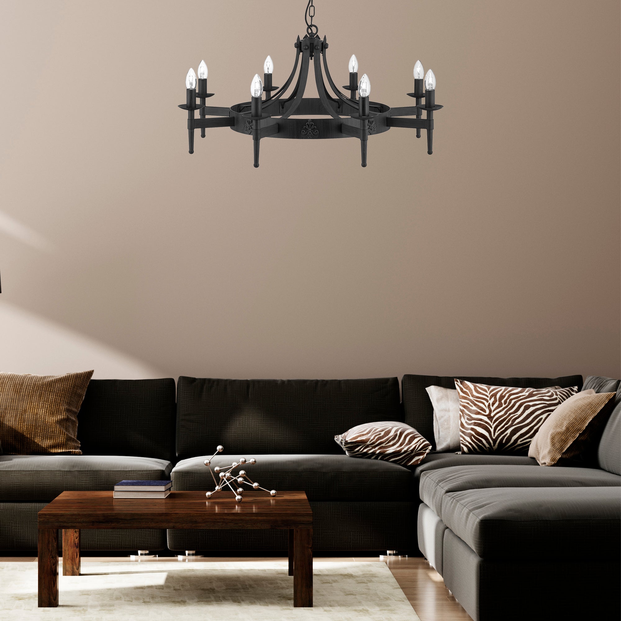 A black, round chandelier hanging above a dark grey sectional sofa in a living room.