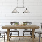 A dining room with a long wooden table and chairs, illuminated by a pendant light.