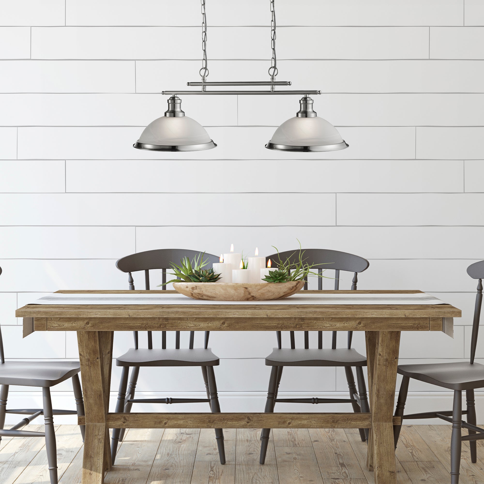 A dining room with a long wooden table and chairs, illuminated by a pendant light.