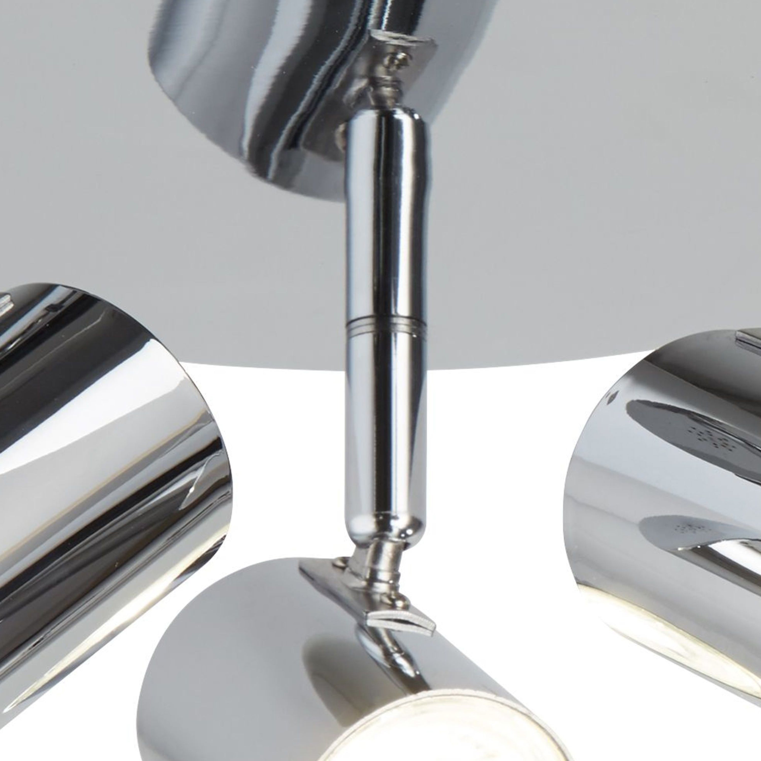 A close-up of a chrome ceiling light, highlighting one of the three adjustable spotlights.