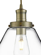 Close-up of the brass fixture and exposed bulb of a cone pendant light.