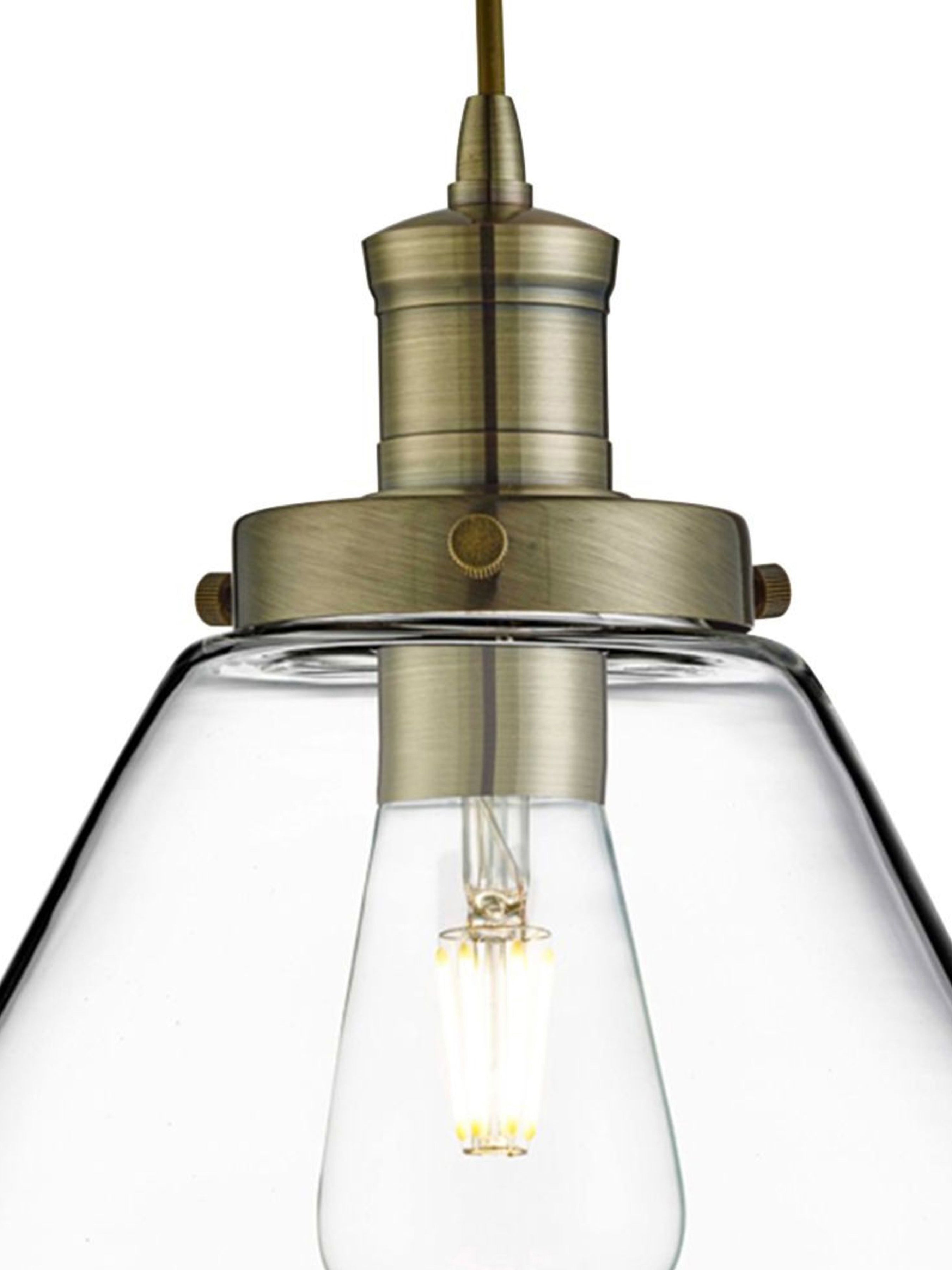 Close-up of the brass fixture and exposed bulb of a cone pendant light.