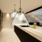 Two brass and glass cone pendant lights illuminate a modern kitchen island.