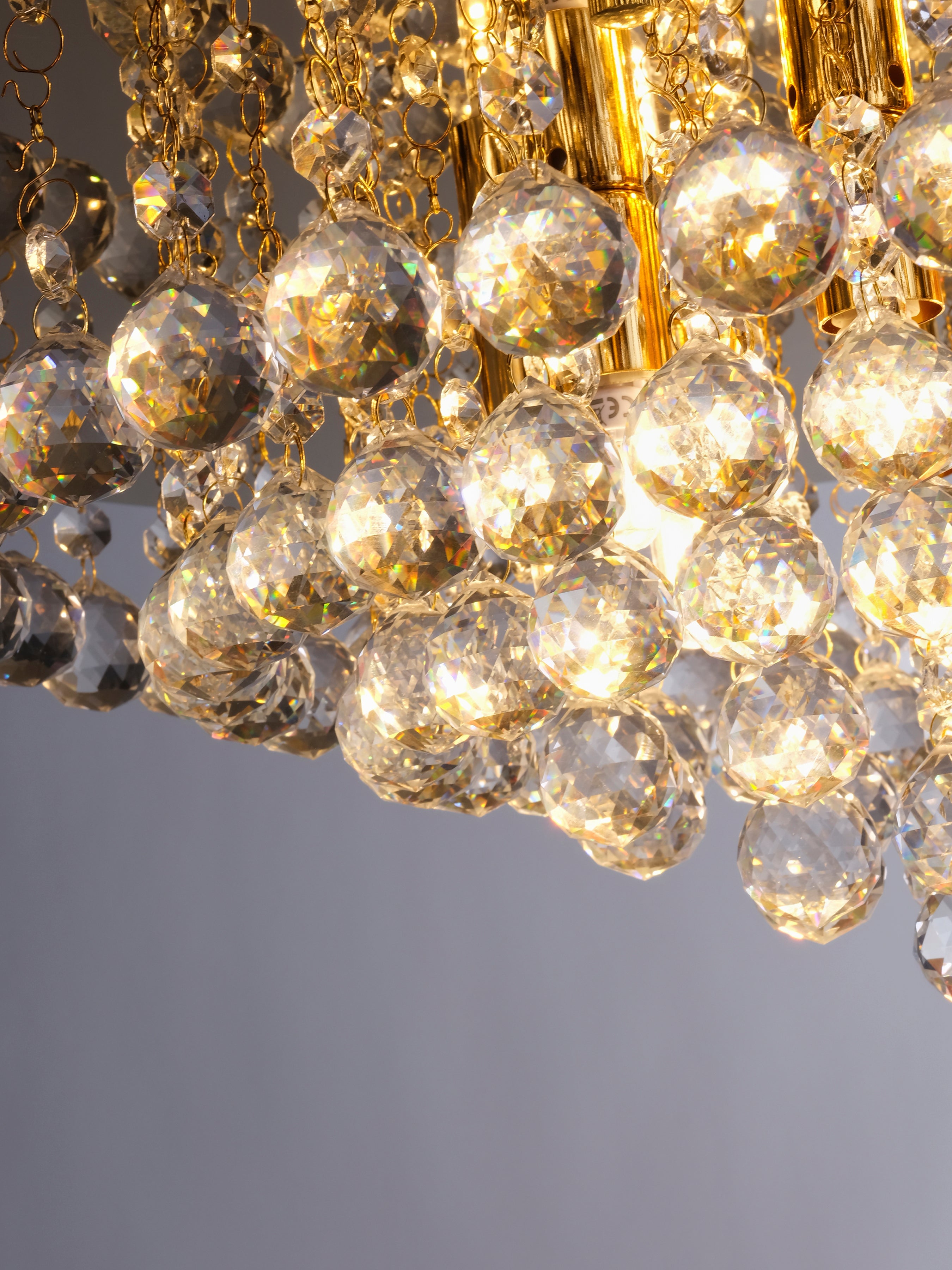 Close-up of sparkling crystal spheres on a gold chandelier, creating a dazzling effect.