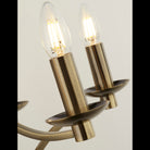 Close-up of two clear candle-shaped bulbs in brass holders.