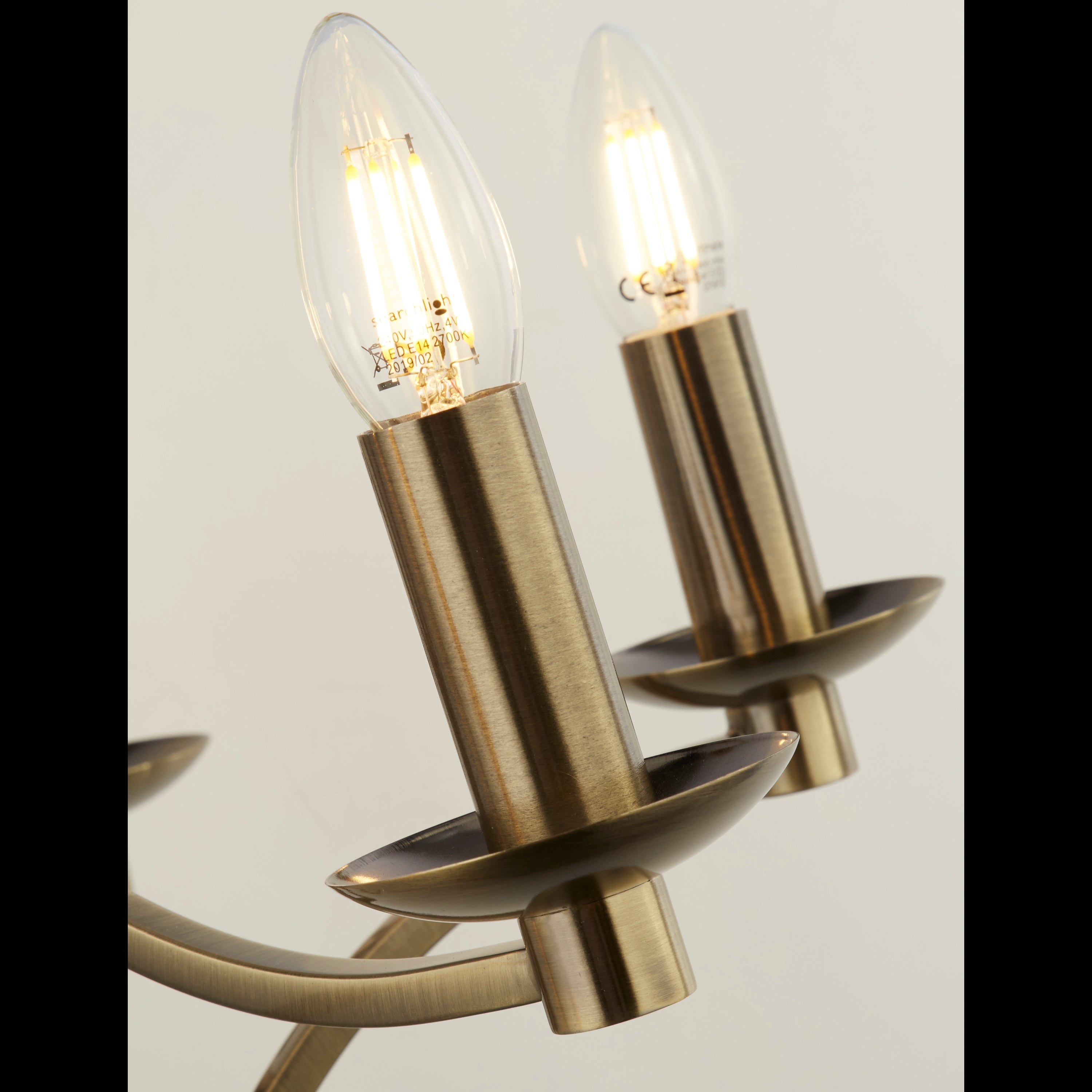 Close-up of two clear candle-shaped bulbs in brass holders.