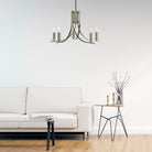 An antique brass chandelier with five lights hangs in a modern living room over a white sofa.