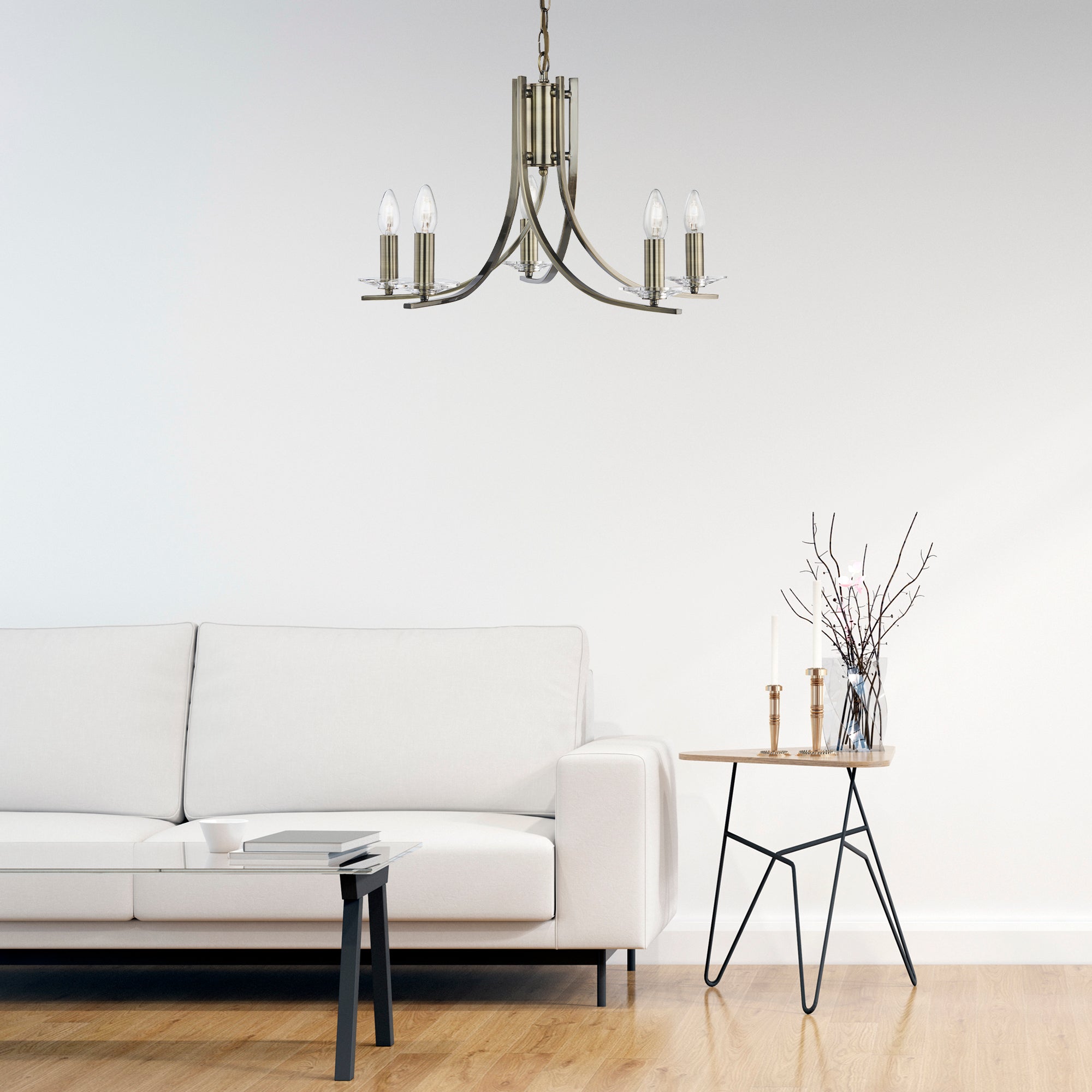 An antique brass chandelier with five lights hangs in a modern living room over a white sofa.