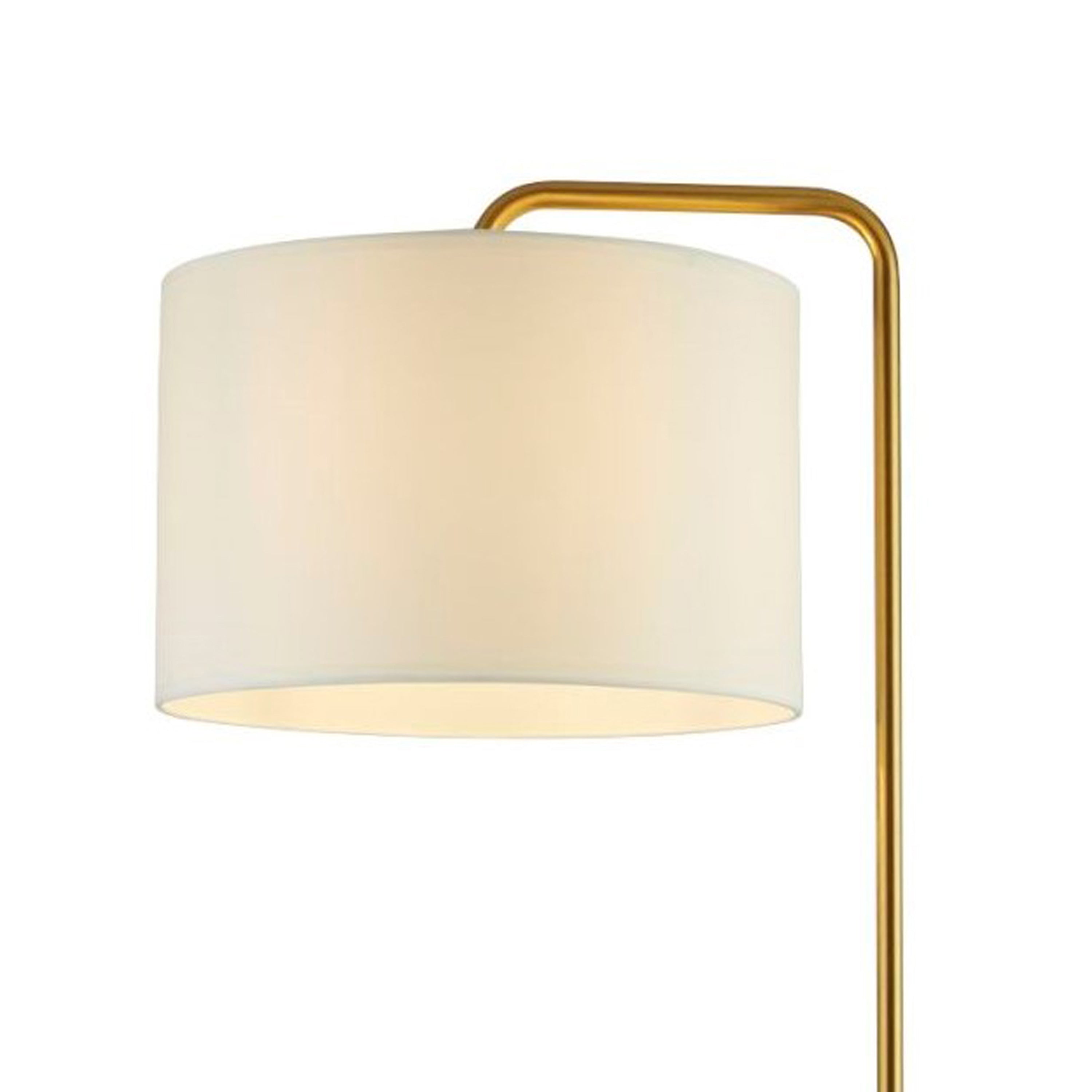 A close-up of a floor lamp's cream drum shade, showing the light-diffusing fabric and gold arm.