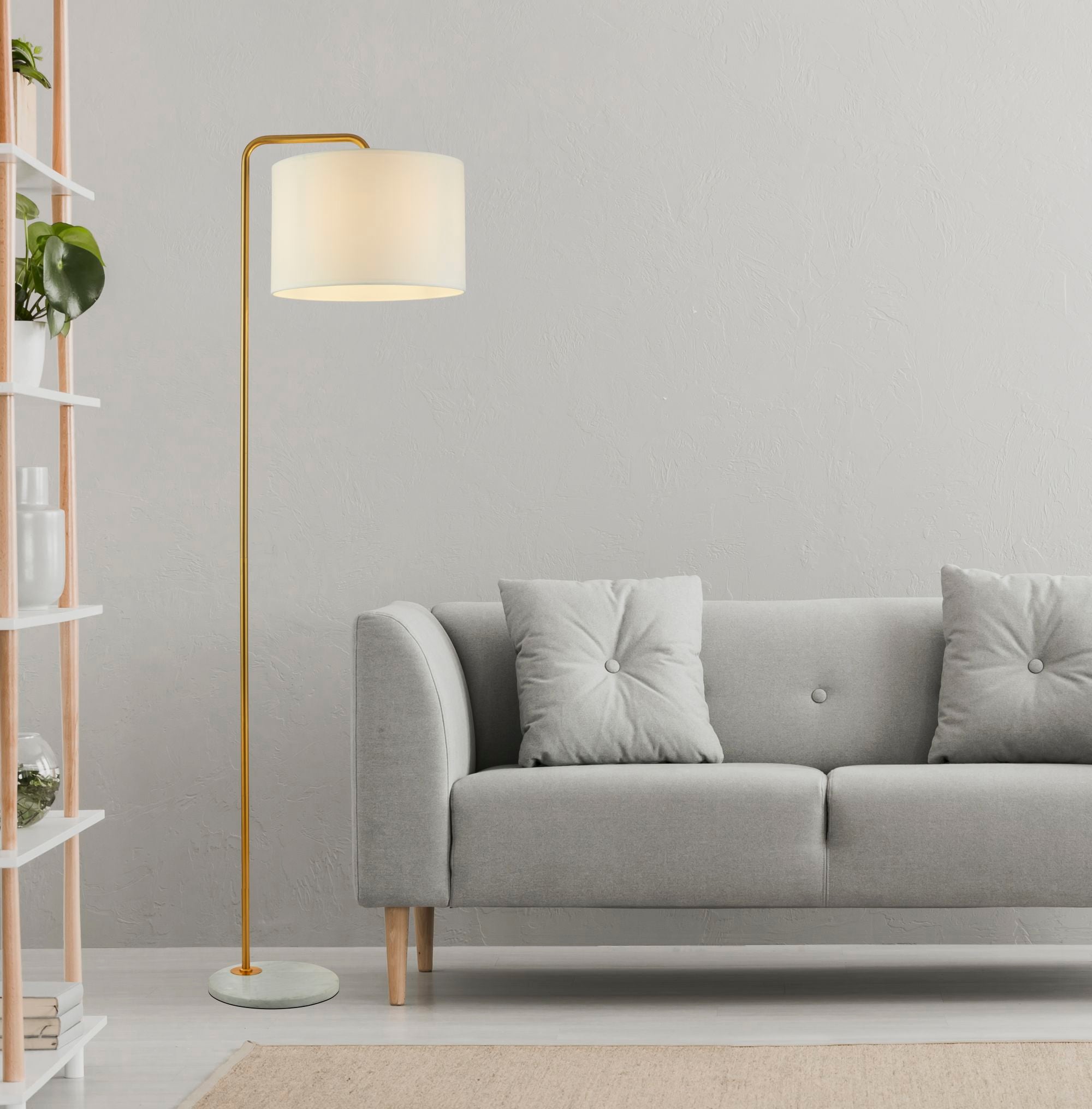 A living room scene with a gold floor lamp illuminating a cozy gray sofa and a white bookshelf.