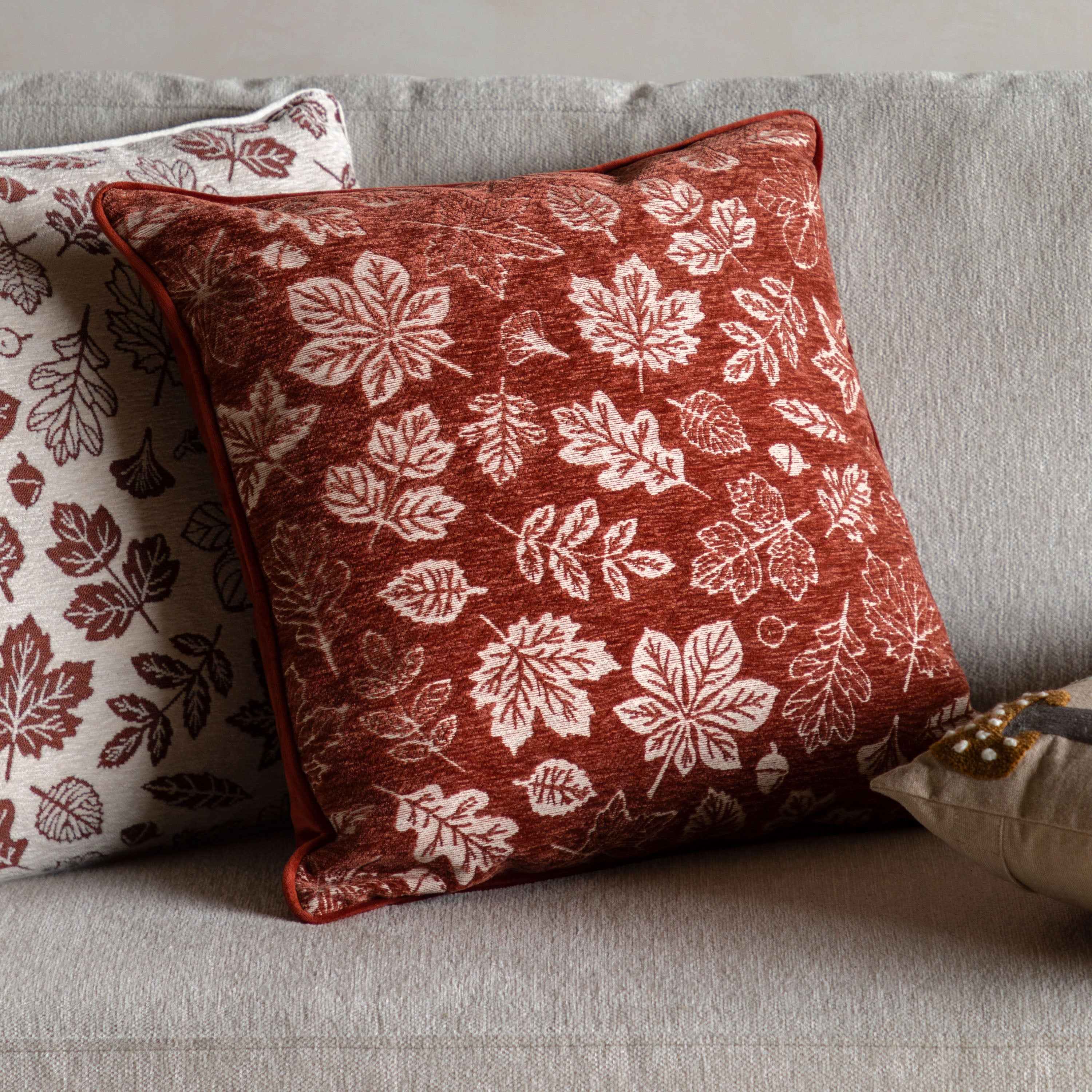 A close-up of a rust-colored cushion with white leaf patterns on a sofa.