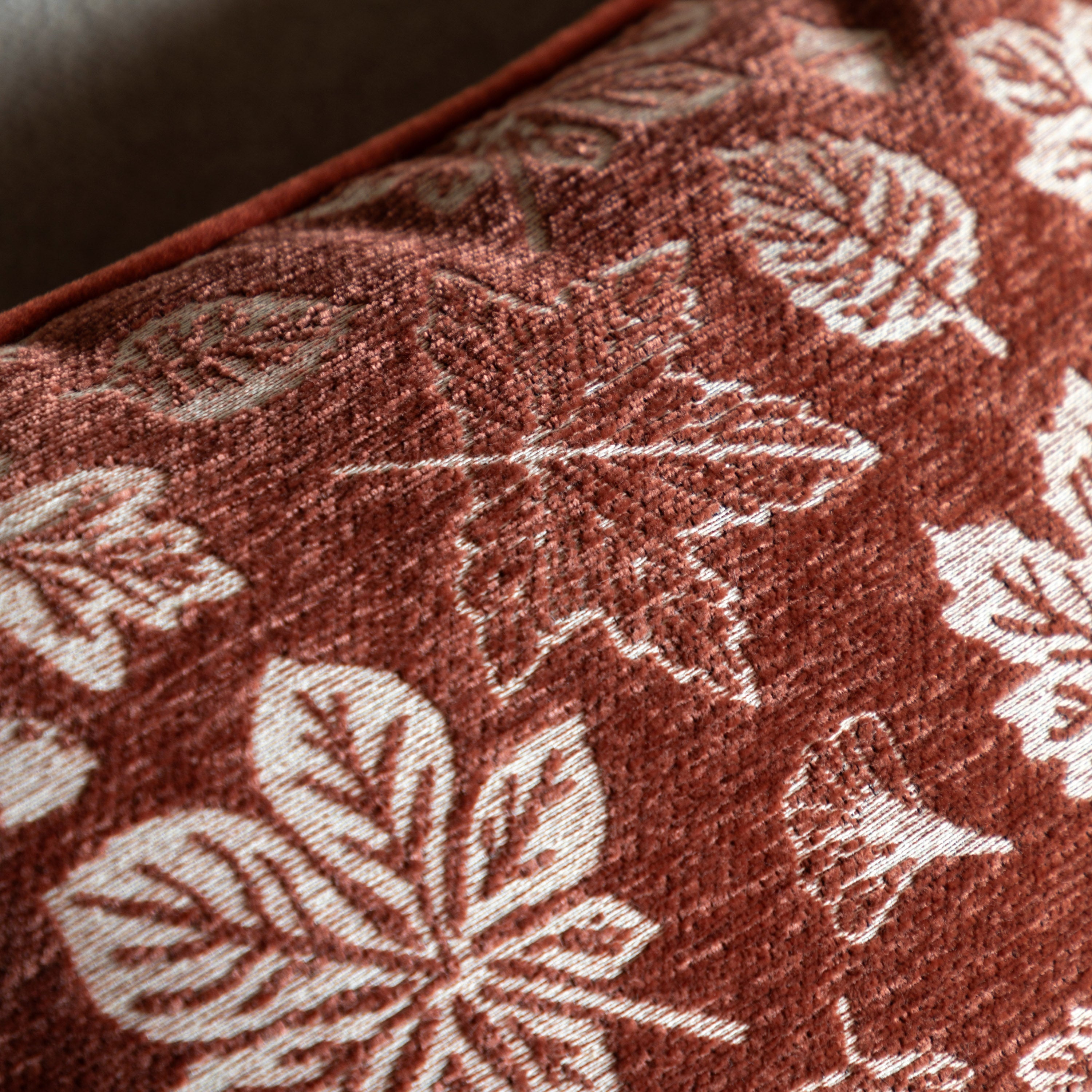 A close-up of the rust-colored cushion fabric, showcasing the detailed leaf patterns.