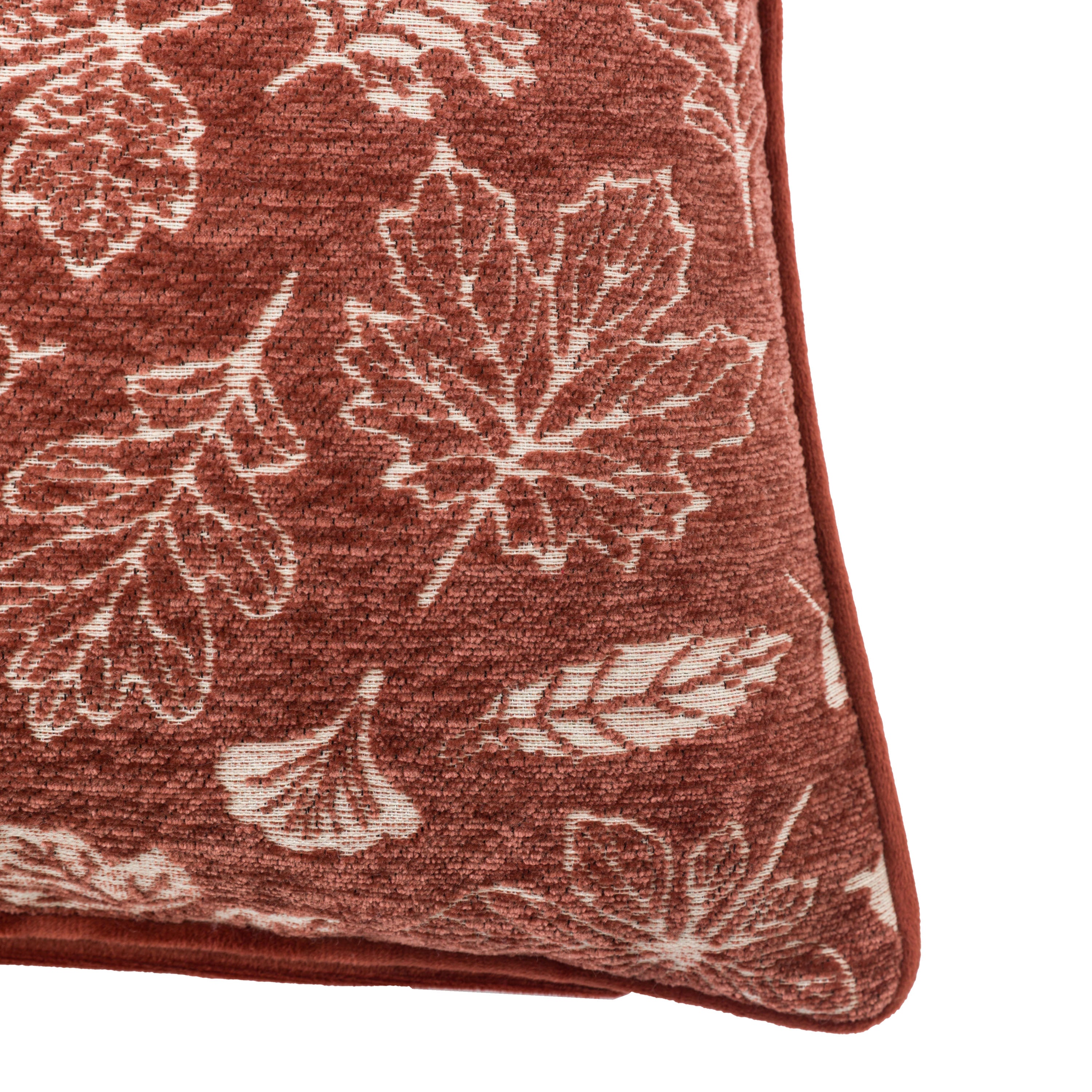 A detailed view of the rust-colored cushion with varied white leaf motifs.